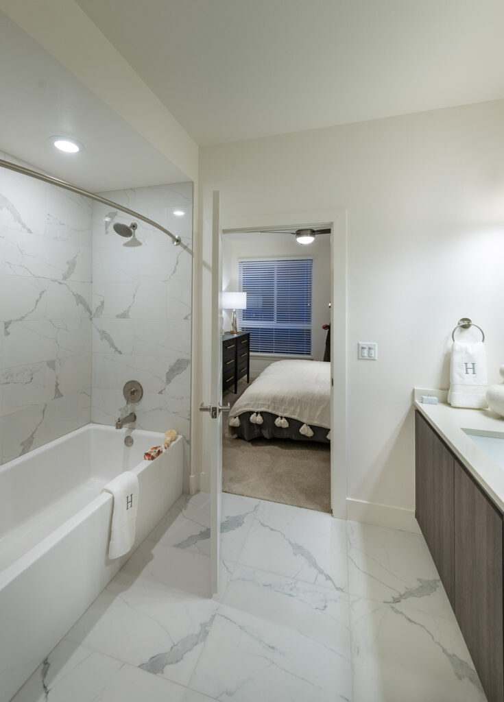 Bathroom with a large tub and a single sink vanity with bedroom access