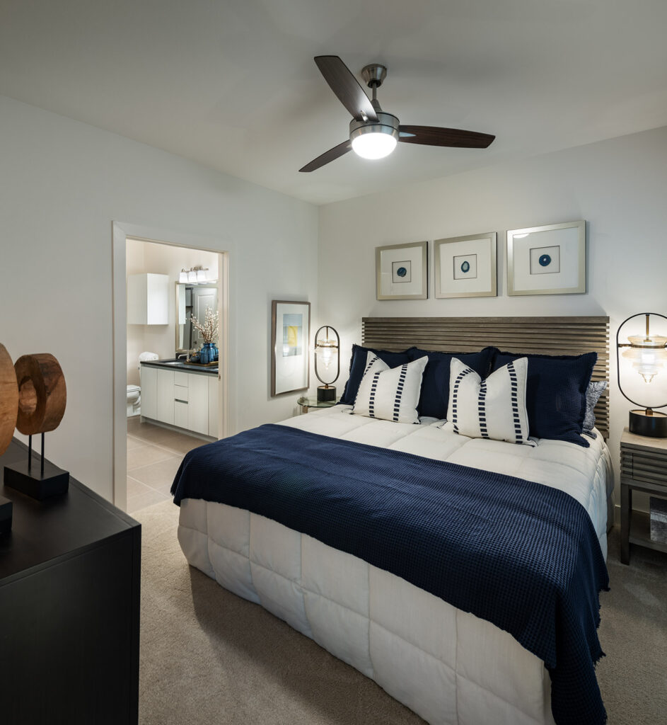 Bedroom with plush carpeting, ceiling fan, and moderne furniture with access to a bathroom