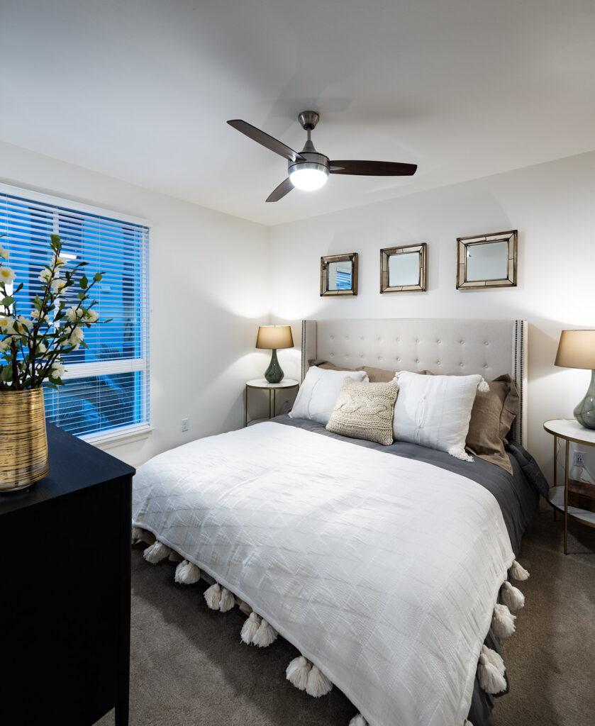 Bedroom with modern furniture, ceiling fan, plush carpet and a large window