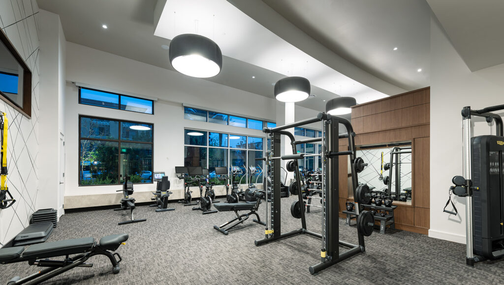 Fitness Center with variety of cardio machines, strength training equipment including a squat rack, and large windows