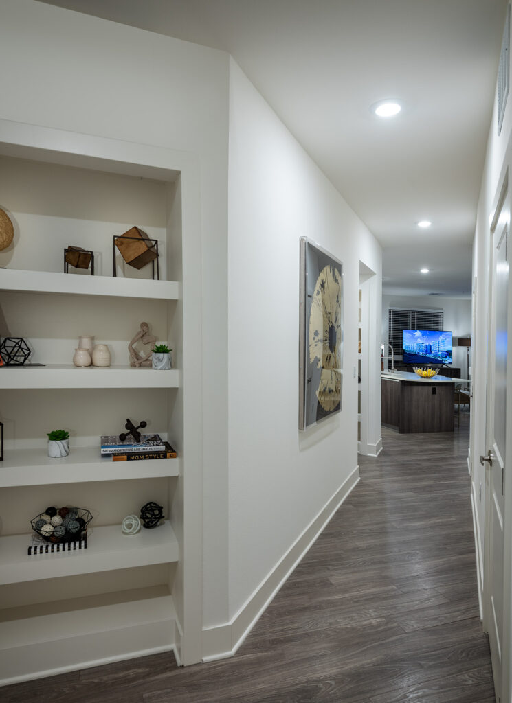 Apartment hallway with built in storage and wood style floors leading to the kitchen