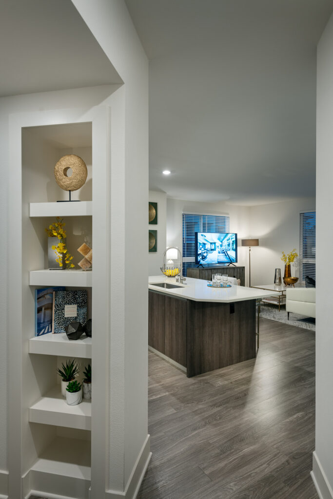 Apartment hallway with wood style floor and built in storage that opens to the kitchen with island and living room