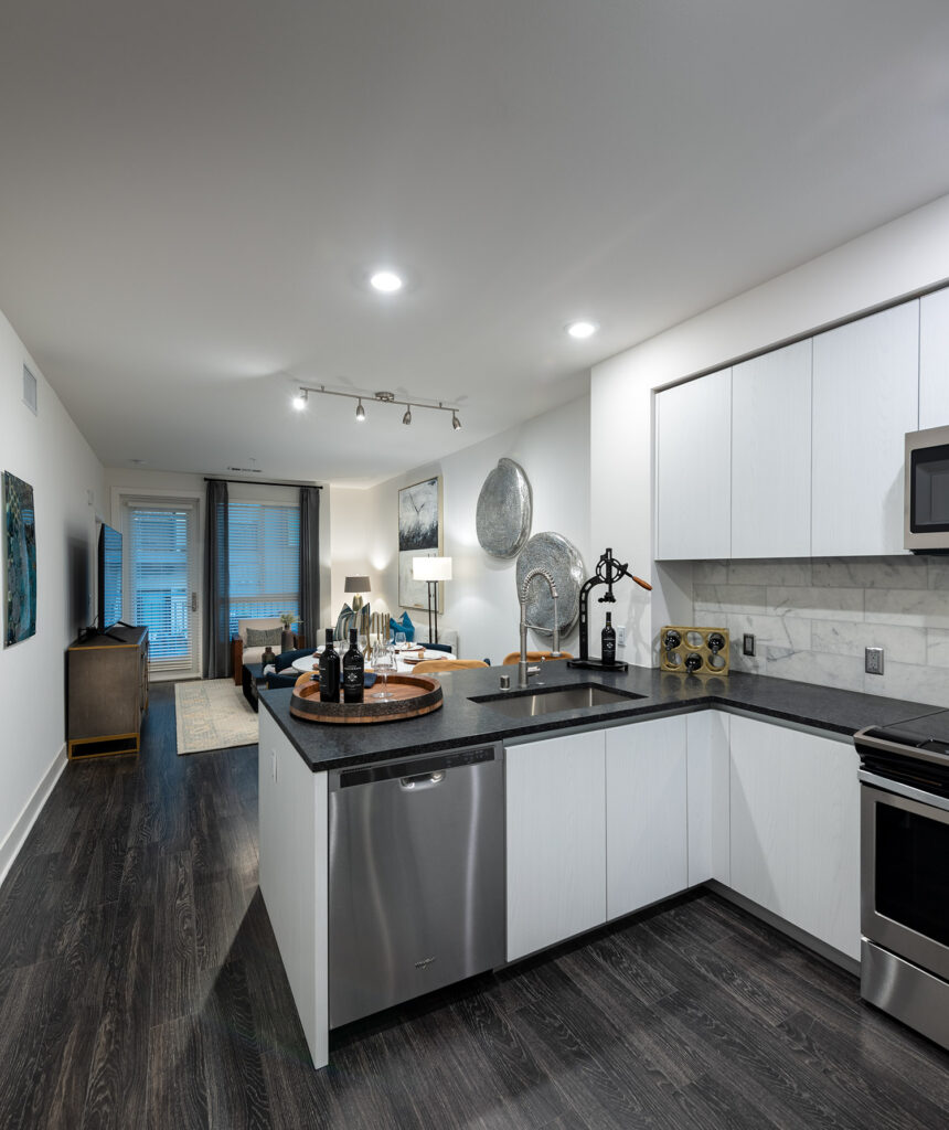 Kitchen with granite counters, stainless steel appliances and wood style floor that is open to the living room with door to a balcony