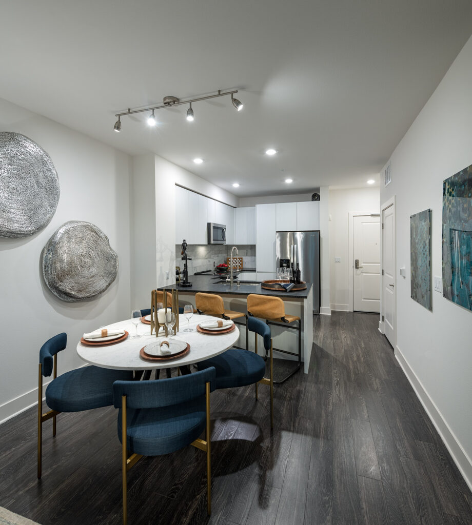 Dining area with wood style floors and designer lighting that is open to the kitchen with granite counters and stainless steel appliances