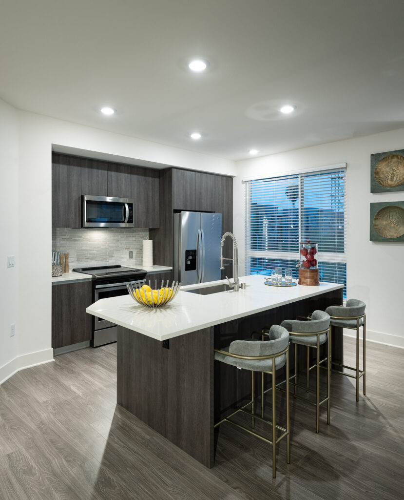 Kitchen with quartz counters, island with bar seating, large window and stainless steel appliances