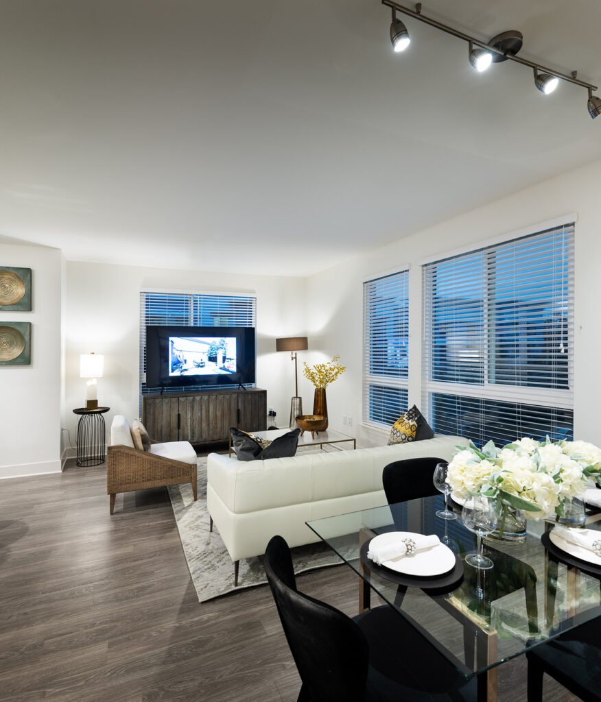 Living room with wood style flooring, large windows, modern furniture and is open to the dining area