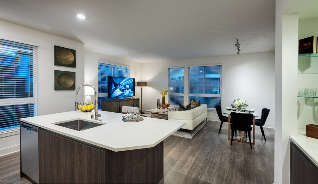 Kitchen with island and quartz counters that is open to the living/dining area with modern furniture and wood style flooring