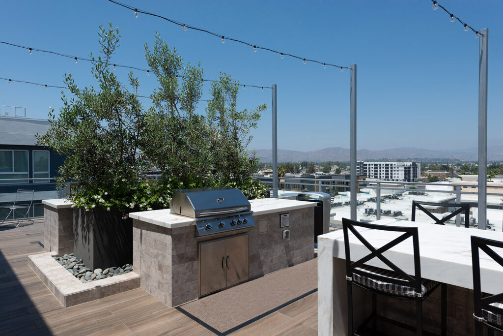 Rooftop kitchen and grill area with family style seating and patio lights